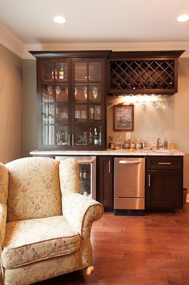 Cette image montre un petit bar de salon avec évier linéaire traditionnel en bois foncé avec un évier encastré, un plan de travail en granite, une crédence multicolore et un sol en bois brun.