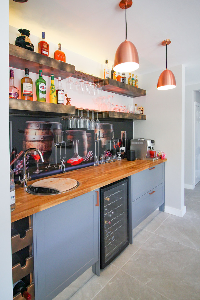 This is an example of an expansive contemporary single-wall wet bar in London with shaker cabinets, grey cabinets, wood worktops, multi-coloured splashback, glass tiled splashback, ceramic flooring, grey floors, green worktops and a built-in sink.