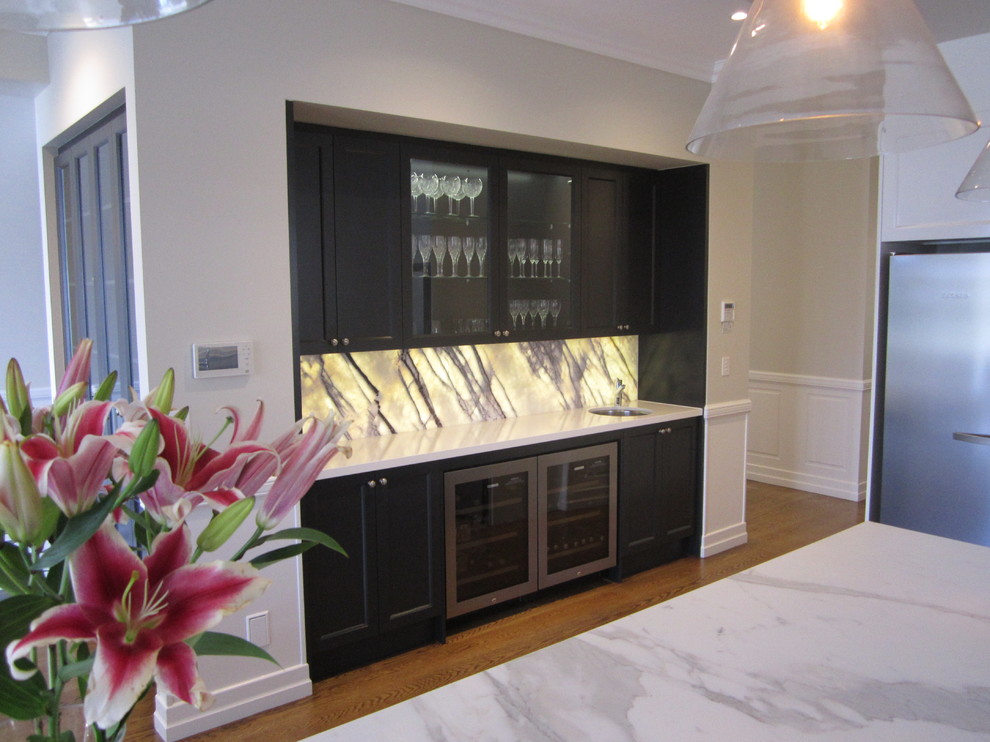 Inredning av en klassisk mellanstor linjär hemmabar med vask, med en undermonterad diskho, luckor med infälld panel, svarta skåp, bänkskiva i koppar, flerfärgad stänkskydd, stänkskydd i marmor, ljust trägolv och brunt golv