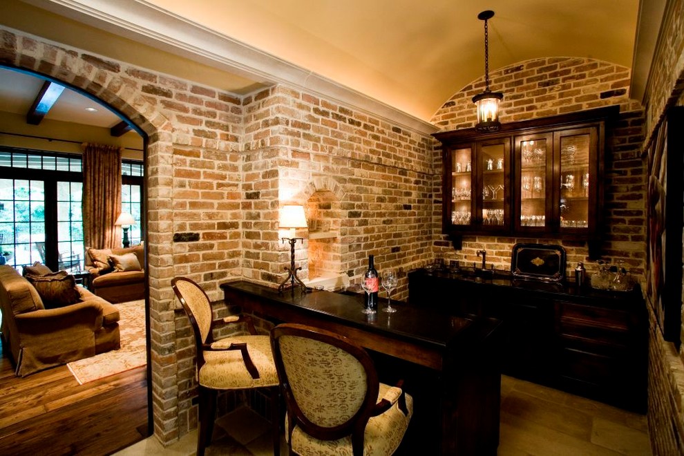 Cette image montre un petit bar de salon parallèle traditionnel en bois foncé avec des tabourets, un évier encastré, un placard à porte vitrée, un plan de travail en bois, une crédence multicolore et un sol en calcaire.