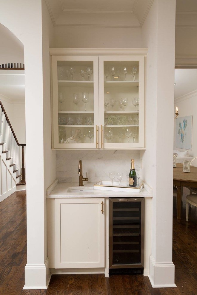Photo of a small contemporary single-wall wet bar in New Orleans with a submerged sink, glass-front cabinets, white cabinets, marble worktops, grey splashback, marble splashback, medium hardwood flooring and brown floors.