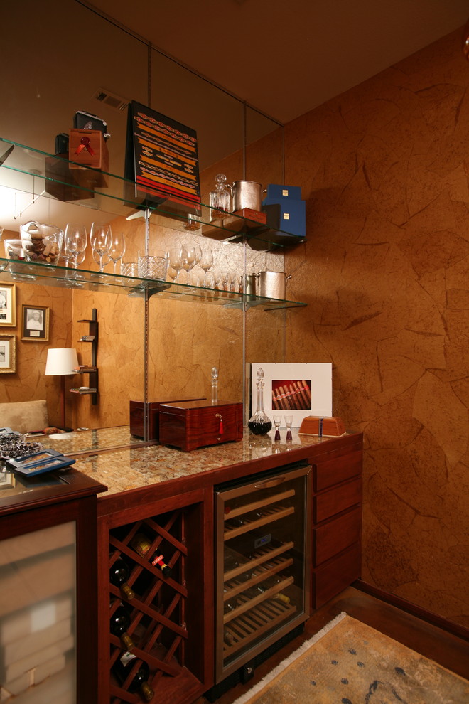 Immagine di un piccolo angolo bar minimalista con ante lisce, ante in legno scuro e top in vetro