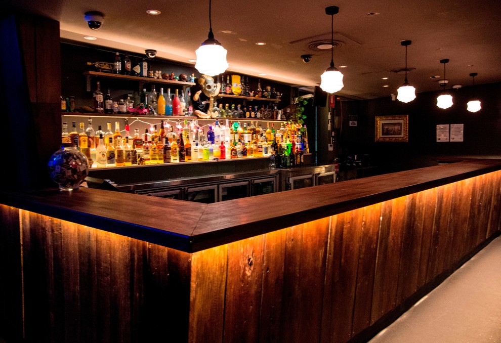 Foto di un angolo bar con lavandino di medie dimensioni con nessun'anta, ante marroni, top in legno e top marrone