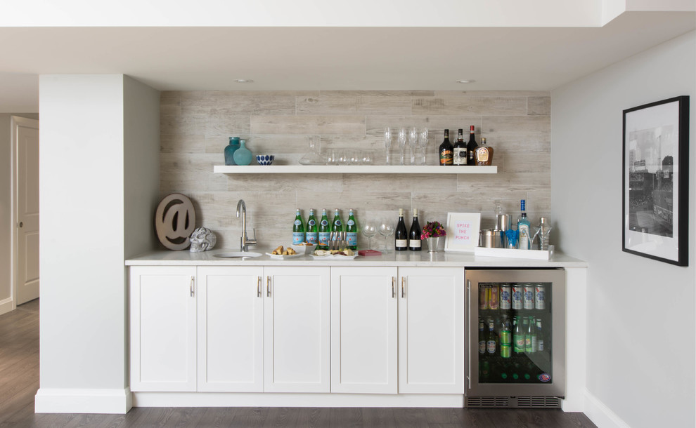 Traditional single-wall wet bar in Toronto with a submerged sink, shaker cabinets, white cabinets, grey splashback and dark hardwood flooring.
