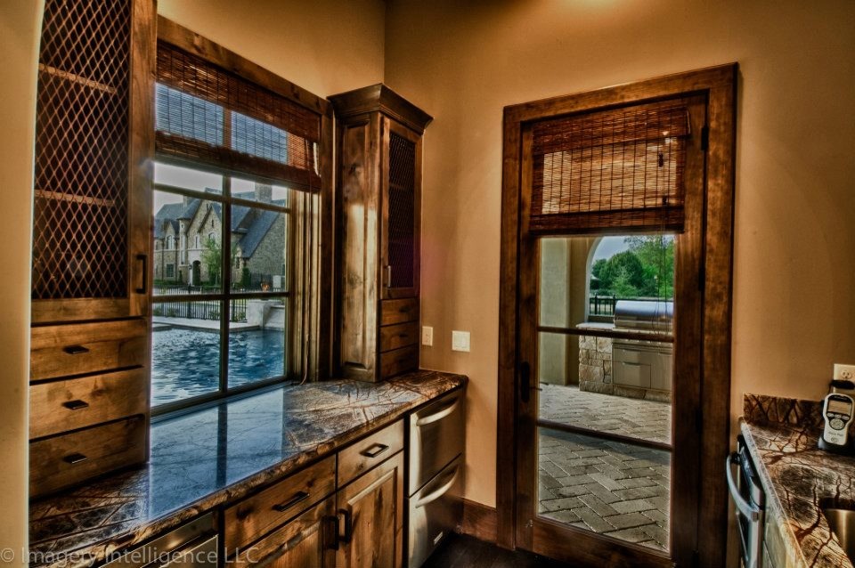 Zweizeilige Mediterrane Hausbar mit Bartresen, Unterbauwaschbecken, hellbraunen Holzschränken, Granit-Arbeitsplatte und dunklem Holzboden in Dallas