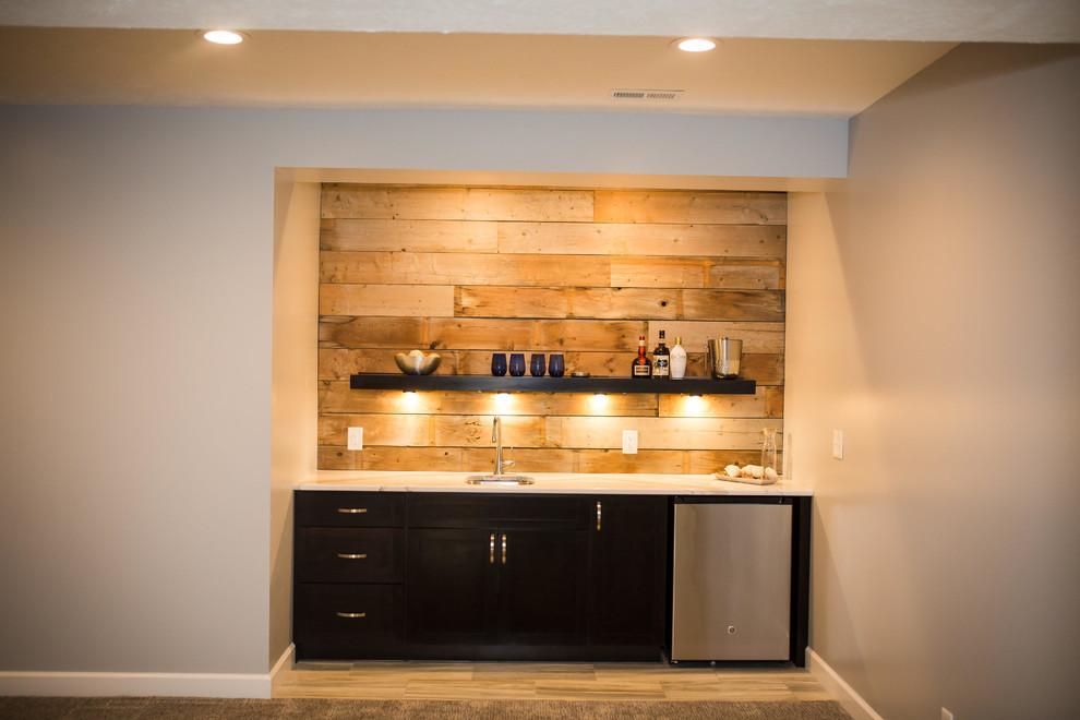 Inspiration for a medium sized rustic single-wall wet bar in Omaha with a submerged sink, flat-panel cabinets, black cabinets, marble worktops, brown splashback, wood splashback and light hardwood flooring.