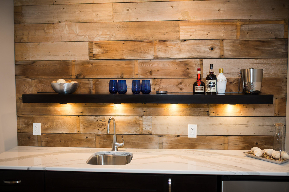 Photo of a medium sized rustic single-wall wet bar in Omaha with a submerged sink, flat-panel cabinets, black cabinets, marble worktops, brown splashback, wood splashback and light hardwood flooring.