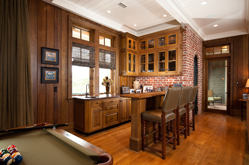 Inspiration for a mid-sized timeless galley medium tone wood floor and brown floor seated home bar remodel in Charleston with raised-panel cabinets, dark wood cabinets, wood countertops and brown countertops