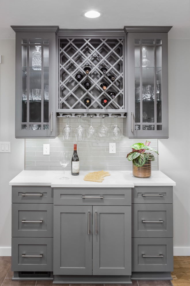 Inspiration for a medium sized classic u-shaped home bar in Seattle with shaker cabinets, grey cabinets, engineered stone countertops, grey splashback, glass tiled splashback, white worktops, no sink, light hardwood flooring and beige floors.