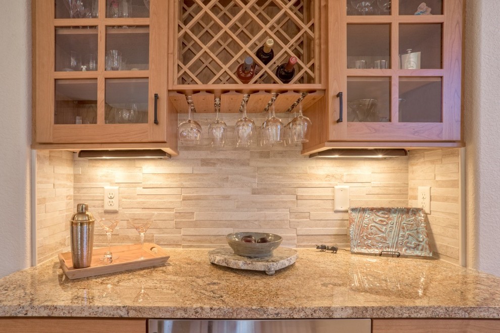 Small modern single-wall wet bar in Denver with no sink, glass-front cabinets, light wood cabinets, granite worktops, beige splashback, stone tiled splashback and light hardwood flooring.