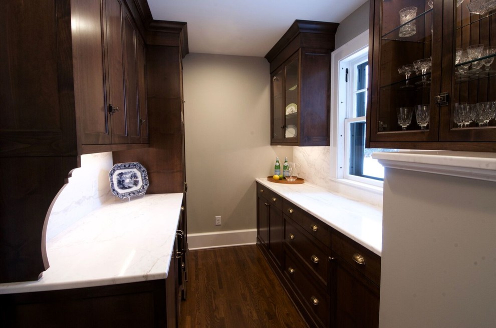Exempel på en mellanstor klassisk vita parallell vitt hemmabar med vask, med luckor med glaspanel, skåp i mörkt trä, bänkskiva i kvarts, vitt stänkskydd, stänkskydd i marmor, mörkt trägolv och brunt golv