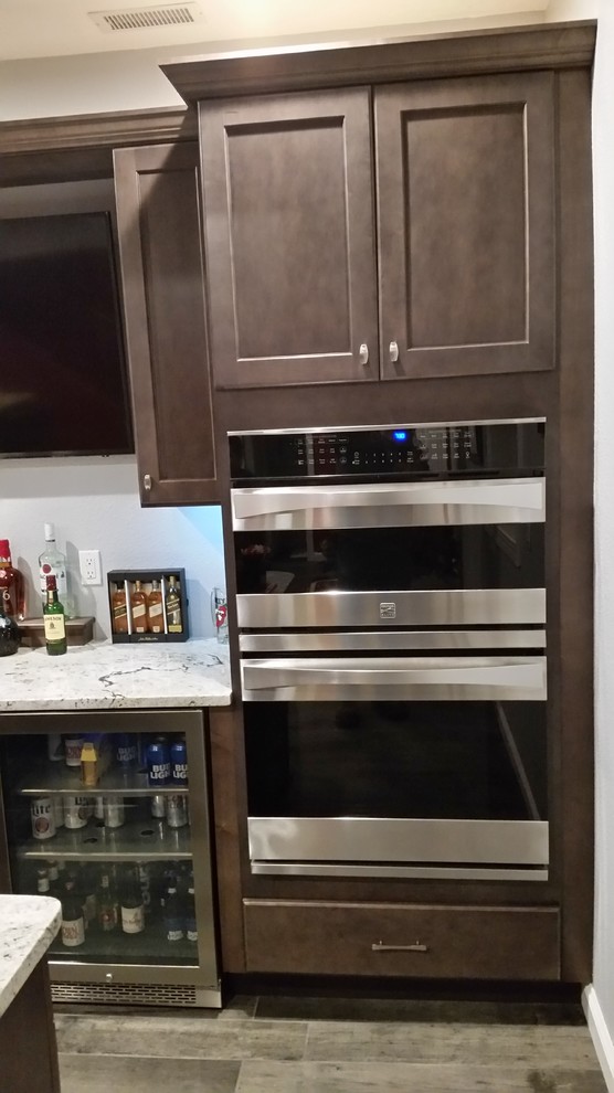 Medium sized classic u-shaped wet bar in Other with shaker cabinets, dark wood cabinets and granite worktops.