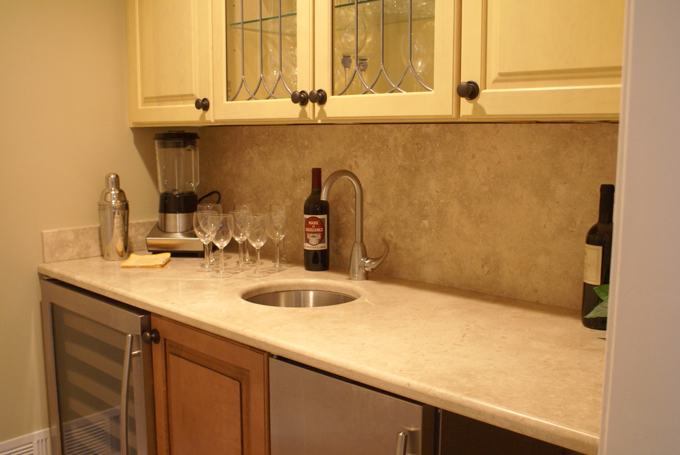 Inspiration for a small classic single-wall wet bar in Newark with a submerged sink, raised-panel cabinets, white cabinets, limestone worktops, beige splashback and stone slab splashback.