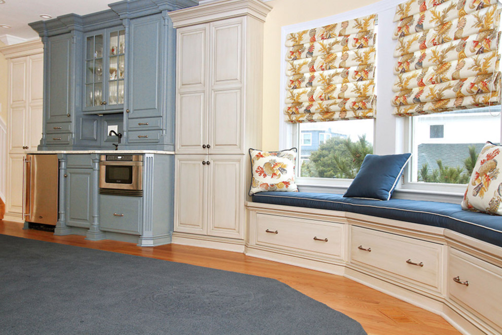 This is an example of a medium sized traditional single-wall wet bar in Other with raised-panel cabinets, blue cabinets, light hardwood flooring and brown floors.