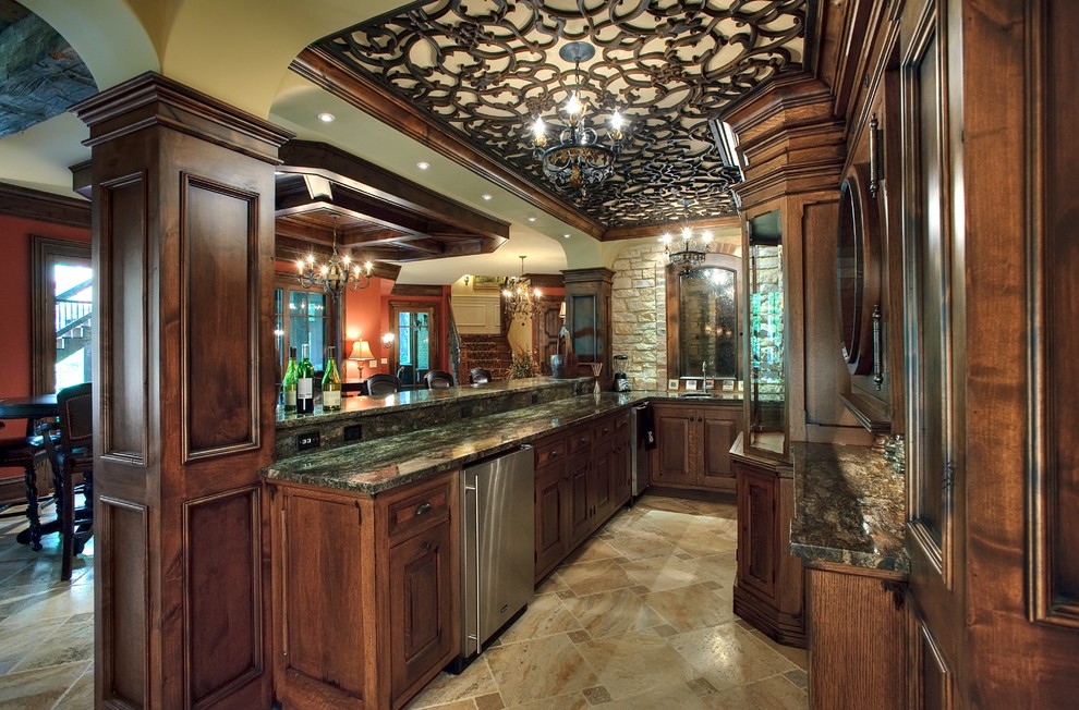 Classic u-shaped wet bar in Chicago with a submerged sink, raised-panel cabinets, dark wood cabinets and beige floors.