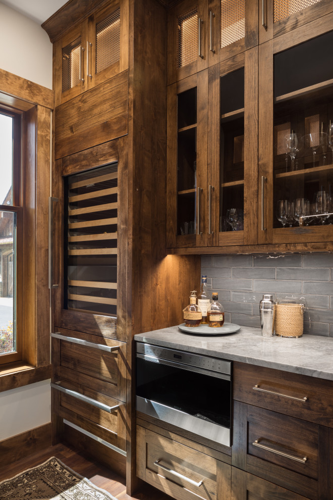 Imagen de bar en casa rústico con armarios tipo vitrina y puertas de armario marrones