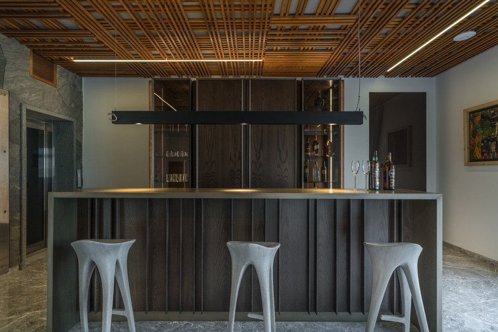 Imagen de bar en casa con barra de bar de galera contemporáneo con armarios con paneles lisos, puertas de armario de madera en tonos medios, salpicadero marrón, salpicadero de madera, suelo gris y encimeras grises