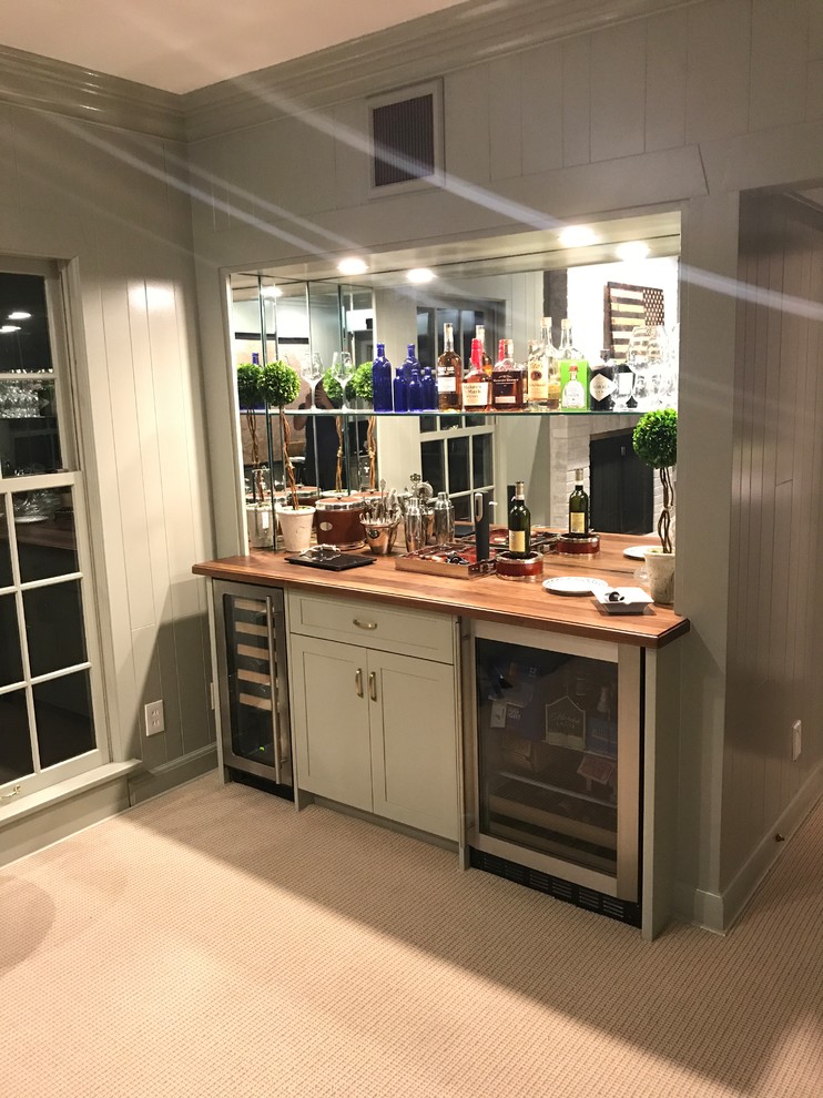 Design ideas for a medium sized traditional single-wall wet bar in St Louis with no sink, shaker cabinets, white cabinets, wood worktops, mirror splashback, carpet, beige floors and brown worktops.