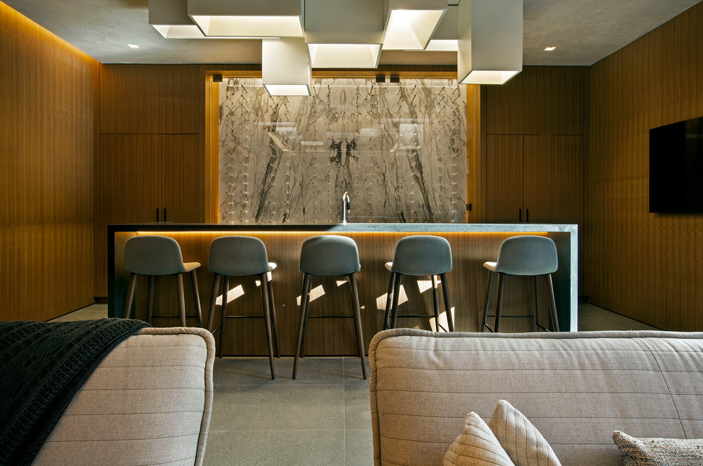 Moderne Hausbar in U-Form mit Bartheke, flächenbündigen Schrankfronten, hellbraunen Holzschränken, grauem Boden und grauer Arbeitsplatte in Denver