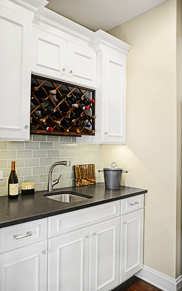 Mid-sized trendy single-wall dark wood floor wet bar photo in Other with an undermount sink, recessed-panel cabinets, white cabinets, granite countertops, beige backsplash and subway tile backsplash