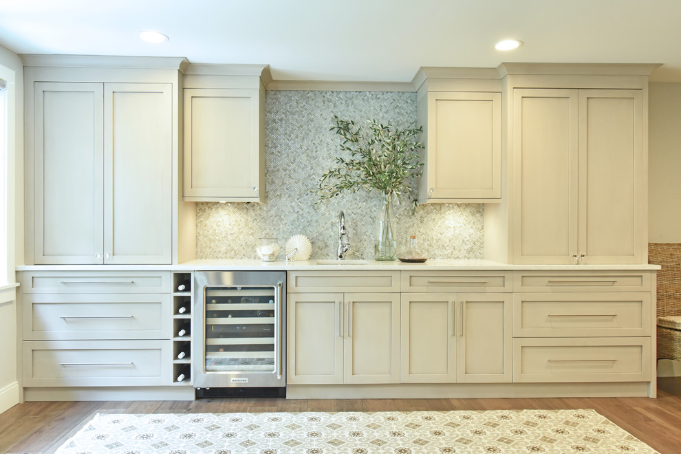 Photo of a medium sized classic single-wall wet bar in Salt Lake City with a submerged sink, recessed-panel cabinets, mosaic tiled splashback, dark hardwood flooring, brown floors, white worktops, grey cabinets, engineered stone countertops and grey splashback.