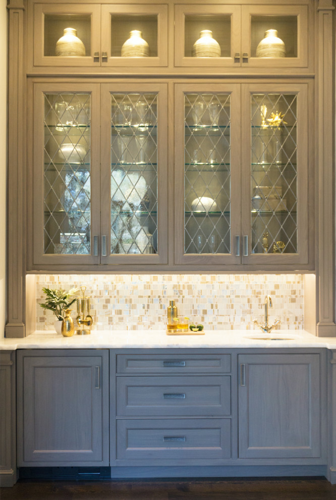 Idéer för en mellanstor klassisk vita linjär hemmabar med vask, med en undermonterad diskho, luckor med infälld panel, grå skåp, bänkskiva i kvartsit, gult stänkskydd, glaspanel som stänkskydd, mörkt trägolv och brunt golv