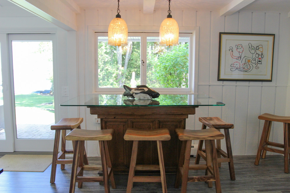 Cette photo montre un bar de salon bord de mer en bois brun de taille moyenne avec des tabourets, un plan de travail en verre, un sol en vinyl et un sol gris.