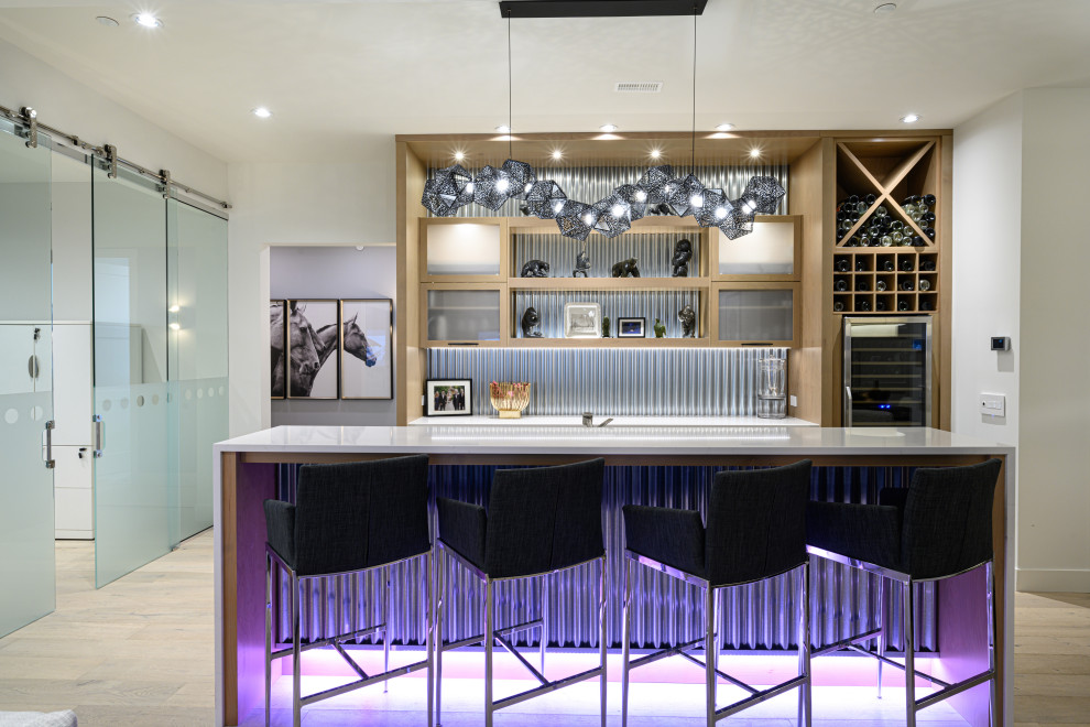 Example of a trendy galley medium tone wood floor and brown floor seated home bar design in Other with glass-front cabinets, light wood cabinets, gray backsplash, metal backsplash and white countertops