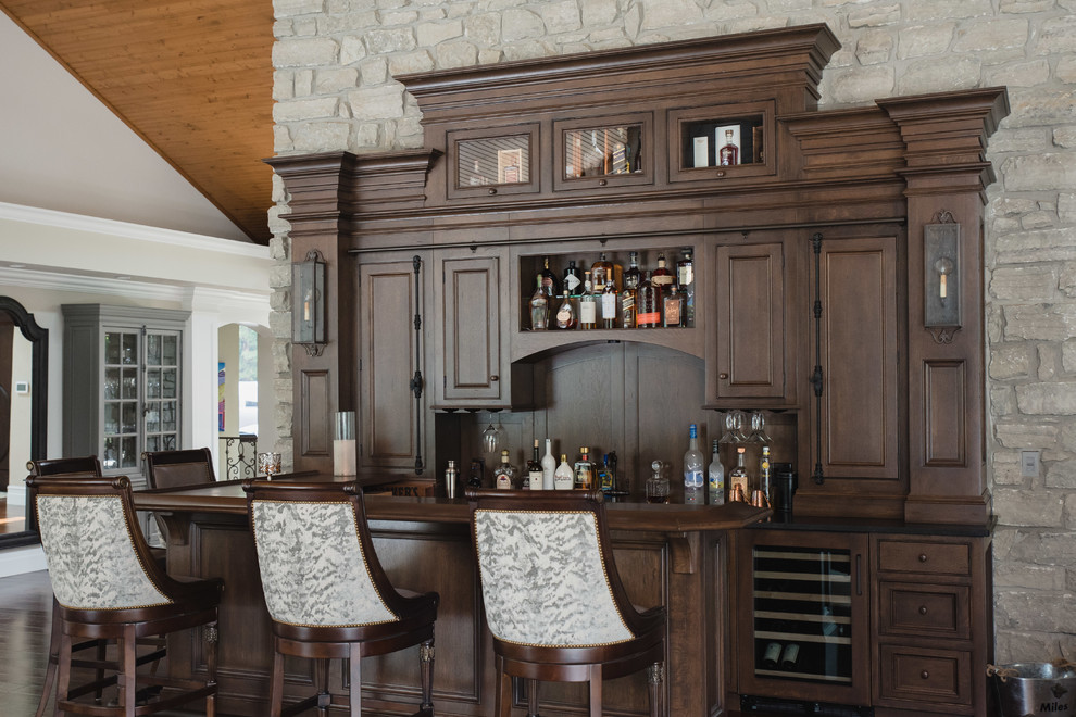 Пример оригинального дизайна: п-образный домашний бар в классическом стиле с барной стойкой, фасадами с утопленной филенкой, темными деревянными фасадами, деревянной столешницей, коричневым фартуком, фартуком из дерева и коричневой столешницей