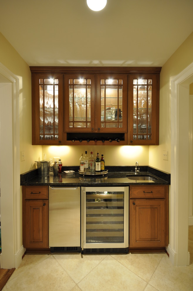 Diseño de bar en casa tradicional renovado con armarios tipo vitrina, puertas de armario de madera oscura, encimera de granito y suelo de baldosas de cerámica