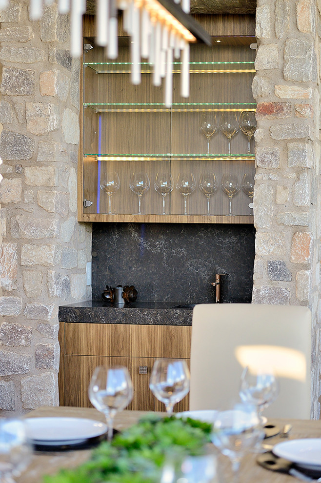 Foto di un angolo bar con lavandino stile americano di medie dimensioni con ante lisce, ante in legno scuro, top in granito, paraspruzzi nero, paraspruzzi in lastra di pietra e top nero