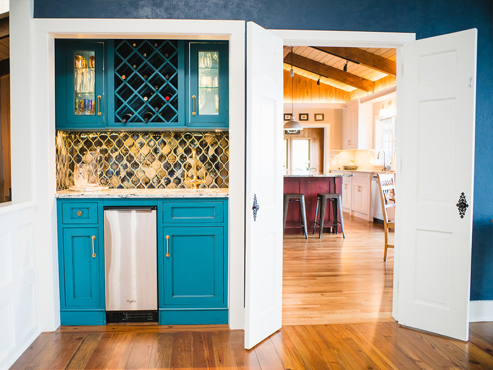 Example of a small transitional single-wall medium tone wood floor wet bar design in Other with an undermount sink, glass-front cabinets, blue cabinets, granite countertops, multicolored backsplash and ceramic backsplash