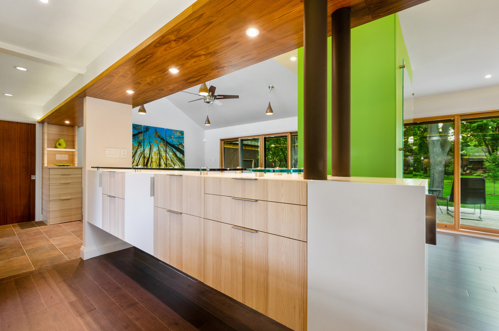 Foto di un angolo bar minimalista di medie dimensioni con ante lisce, ante in legno chiaro, top in vetro e pavimento in legno massello medio