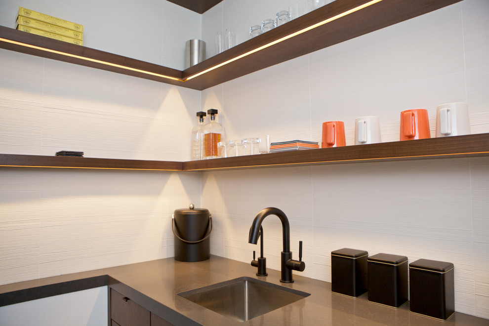 Foto på en mellanstor funkis linjär hemmabar med vask, med en undermonterad diskho, släta luckor, skåp i mörkt trä, bänkskiva i kvarts, vitt stänkskydd, stänkskydd i keramik, mörkt trägolv och svart golv