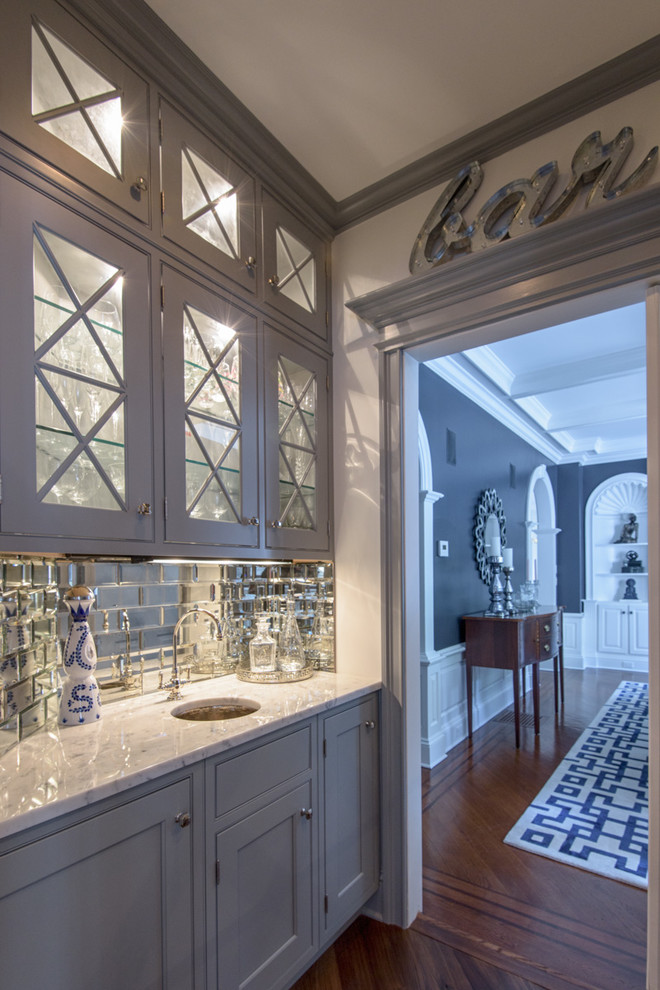 Small transitional single-wall dark wood floor wet bar photo in New York with an undermount sink, glass-front cabinets, gray cabinets, marble countertops, subway tile backsplash and gray countertops