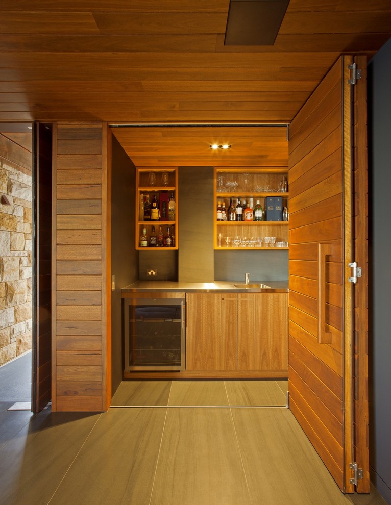 Modelo de bar en casa actual grande con fregadero bajoencimera, armarios abiertos, puertas de armario de madera oscura y encimera de acero inoxidable