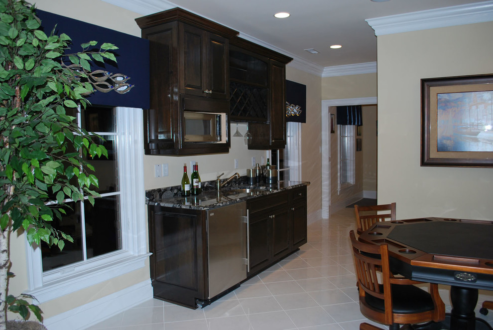 Photo of a medium sized single-wall wet bar in Other with a built-in sink, beaded cabinets, dark wood cabinets, granite worktops and ceramic flooring.