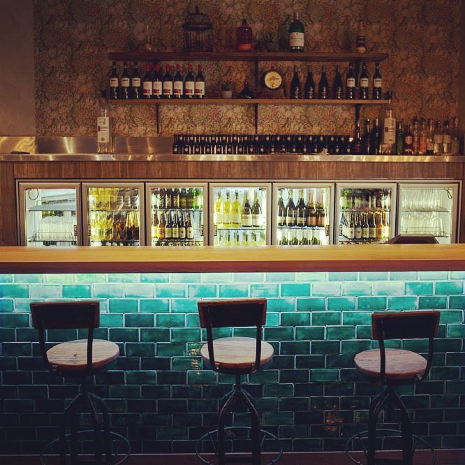 Esempio di un angolo bar con lavandino eclettico di medie dimensioni con ante lisce, ante in legno scuro, top in legno e top beige
