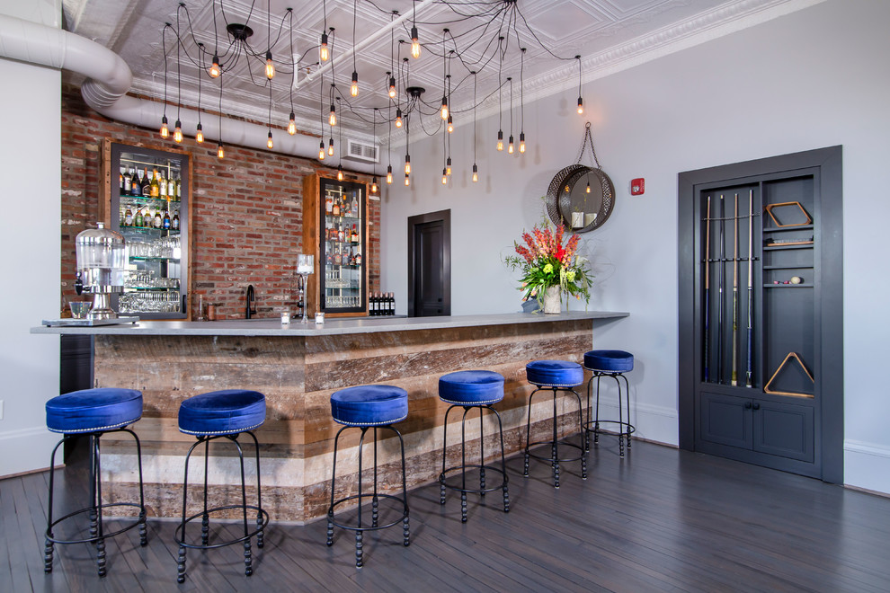 Design ideas for a large industrial galley breakfast bar in Charlotte with concrete worktops, brick splashback, grey worktops, red splashback, dark hardwood flooring, brown floors and a feature wall.