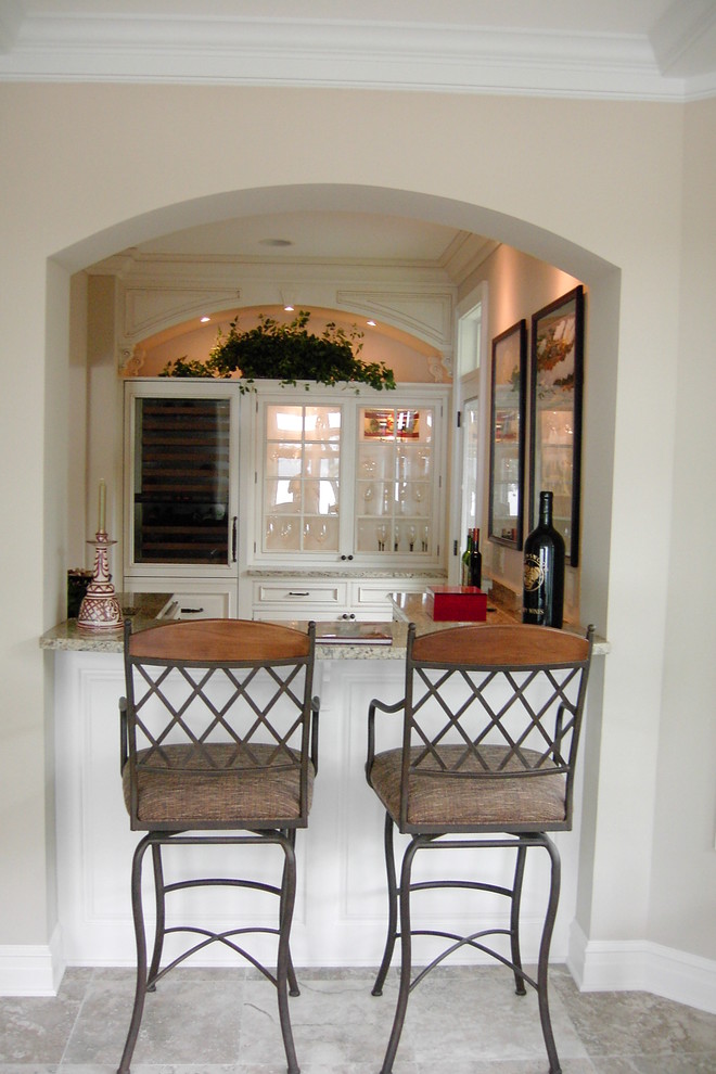Photo of a medium sized traditional single-wall breakfast bar in Milwaukee with glass-front cabinets, white cabinets, travertine flooring and grey floors.