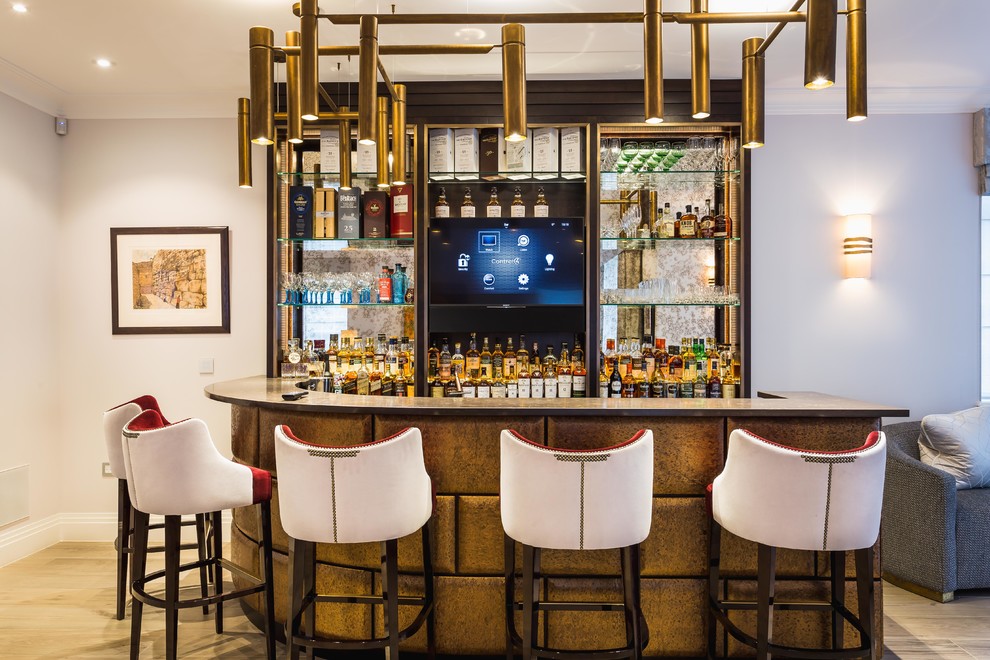 Immagine di un bancone bar tradizionale di medie dimensioni con nessun'anta, paraspruzzi a specchio, parquet chiaro, pavimento beige e top nero