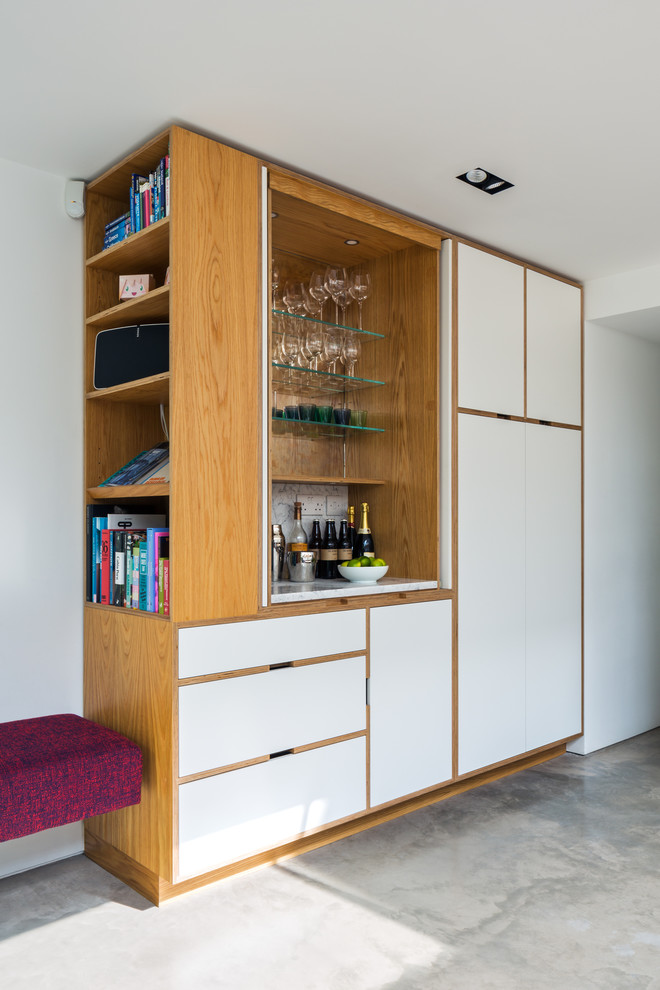 Medium sized modern wet bar in London with flat-panel cabinets, white cabinets, concrete flooring and grey floors.
