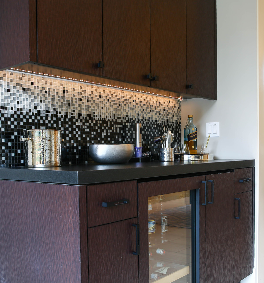 This is an example of a medium sized wet bar in San Francisco with flat-panel cabinets, dark wood cabinets, granite worktops, black splashback and glass tiled splashback.