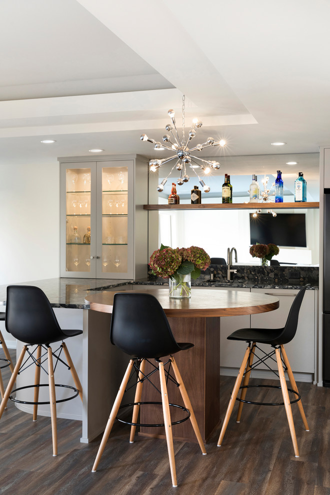 Inspiration for a mid-sized transitional galley dark wood floor and brown floor seated home bar remodel in Minneapolis with an undermount sink, glass-front cabinets, white cabinets, wood countertops and mirror backsplash