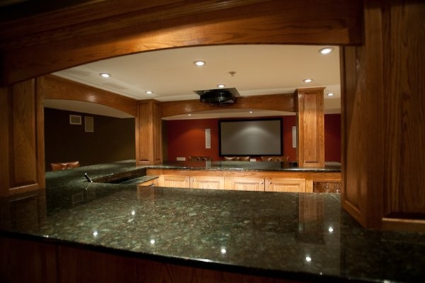 Photo of a large traditional u-shaped breakfast bar in Philadelphia with a submerged sink, raised-panel cabinets, medium wood cabinets, granite worktops, porcelain flooring, grey floors and black worktops.