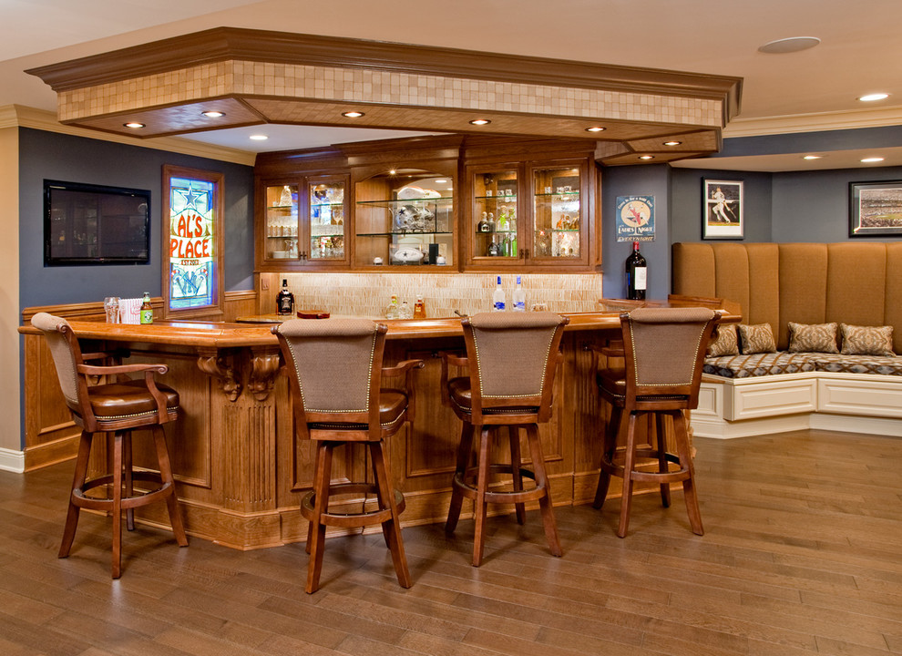 Idee per un grande bancone bar classico con pavimento in legno massello medio, ante con riquadro incassato, ante in legno scuro e paraspruzzi beige