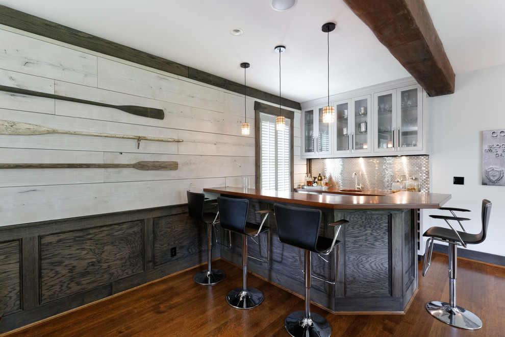 Example of a mid-sized classic u-shaped medium tone wood floor and brown floor wet bar design in Cincinnati with an undermount sink, recessed-panel cabinets, gray cabinets, wood countertops, gray backsplash and metal backsplash