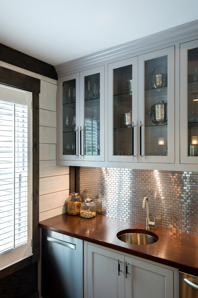 Exempel på en mellanstor klassisk hemmabar med vask, med en undermonterad diskho, luckor med infälld panel, grå skåp, träbänkskiva, mellanmörkt trägolv, grått stänkskydd, stänkskydd i metallkakel och brunt golv
