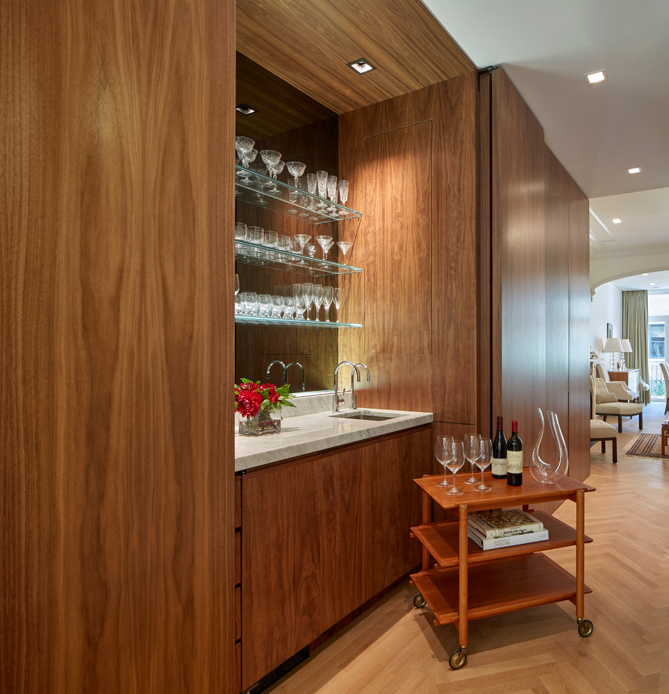 Diseño de bar en casa con fregadero lineal actual con fregadero bajoencimera, armarios con paneles lisos, puertas de armario de madera en tonos medios, salpicadero con efecto espejo y suelo de madera clara