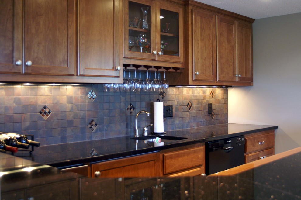 Inspiration for a large classic u-shaped wet bar in Minneapolis with a submerged sink, recessed-panel cabinets, medium wood cabinets, granite worktops, grey splashback and slate splashback.